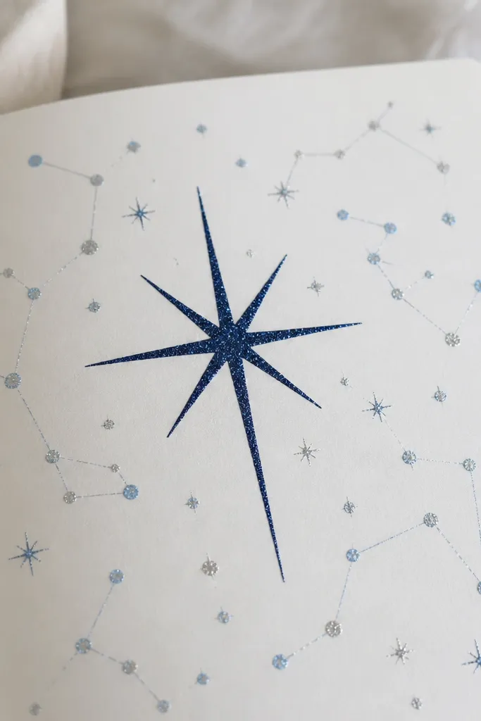 A page with a dark navy heading written in glitter gel pen; around it are small dot constellations connected by faint lines, all in silver and light blue.