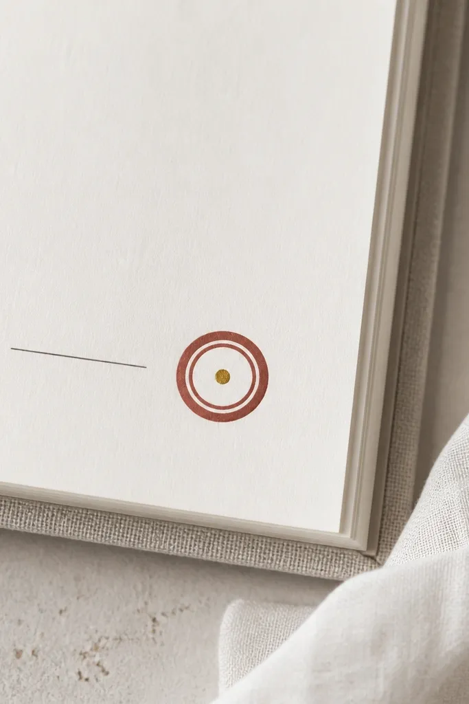A small circular wax-seal look on the page: a ring of muted red-brown washi tape, a slightly thicker outer ring, and a single gold dot in the center. The seal sits beside a short date line.