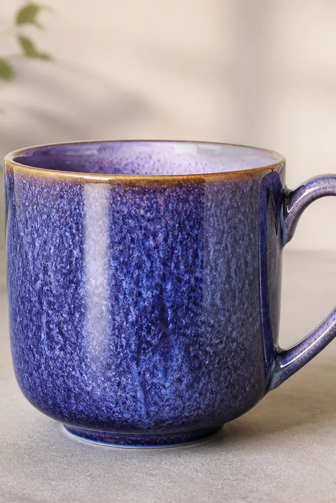 Final mug photographed front-on with strong lighting, showing a blue-violet textured body, lighter lavender highlights, and a delicate gold rim line; coffee-free for a clean reveal.