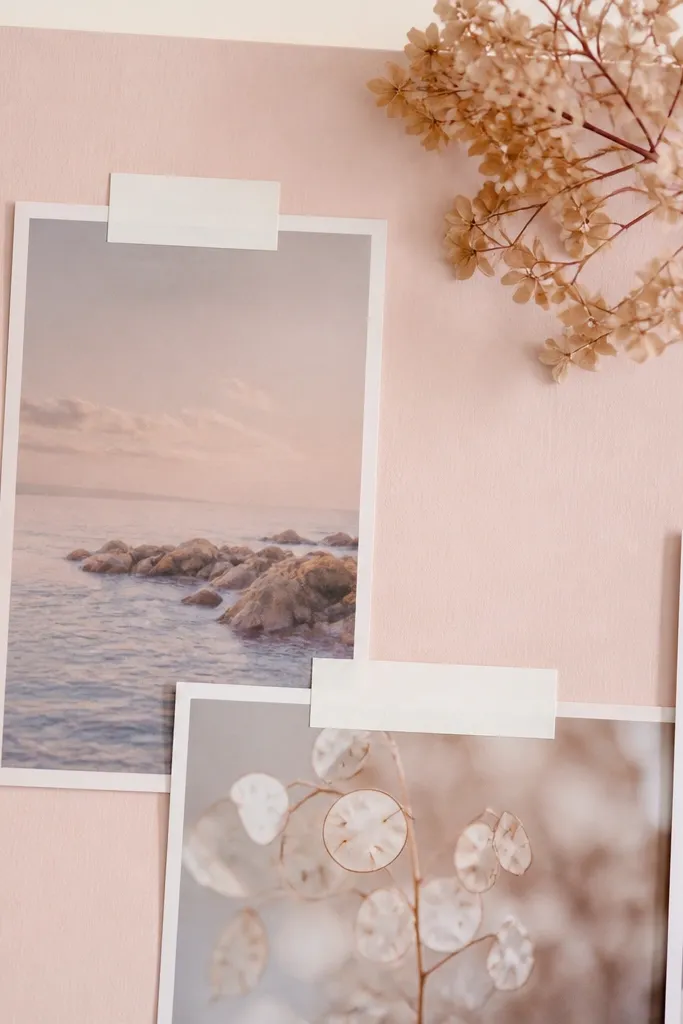 A blush-pink board with a single dried flower cluster in the top corner, pastel photos underneath, and tiny white label stickers with black text.